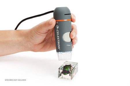Microscopio digitale portatile Celestron in uso su cubo trasparente, connessione USB, alta qualità ottica per immagini dettagliate.